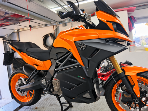 Elektrisch orangefarbenes Motorrad in der Werkstatt.png